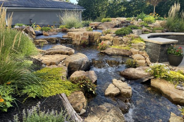patio-side landscaping waterfall with shrubs and flowers