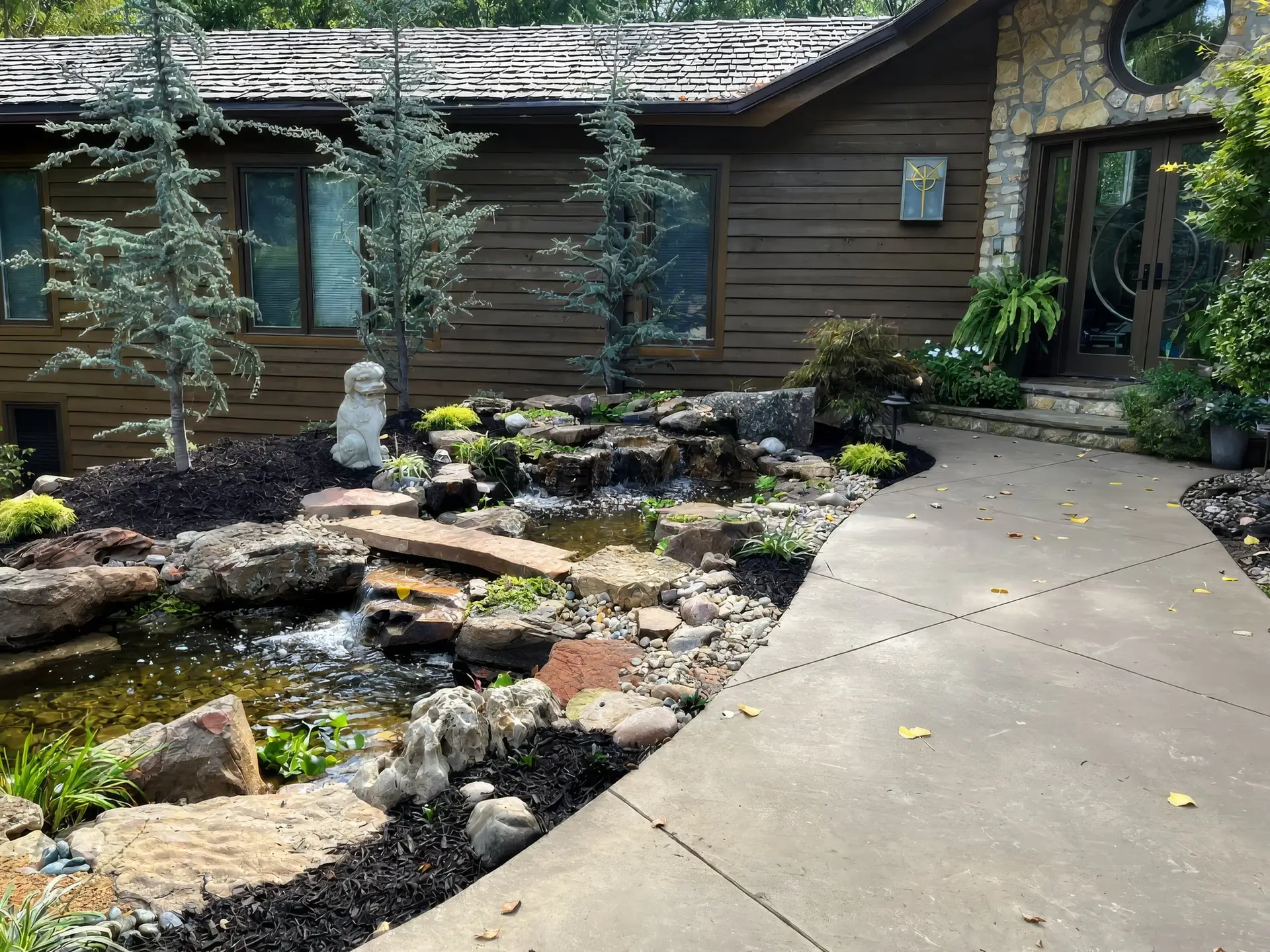 A front-yard pond and stream alongside a curved concrete walk