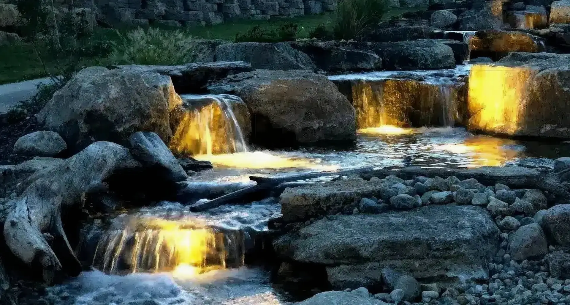 A cascading stream glowing with underwater LED lights after dark
